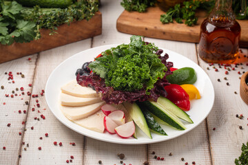 Fresh vegetable and cheese platter with herbs on white plate