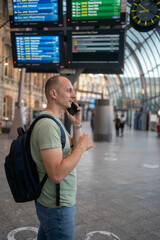 Mature businessman talking on cell phone and carrying suitcase at modern railway station