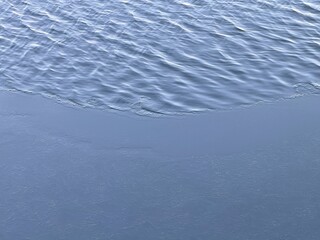 Cold blue river rippling water with thin ice on the shore.