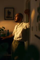 Man thinking indoors in warm evening light. 