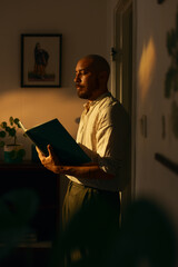Man reading a book  indoors in warm evening light. 