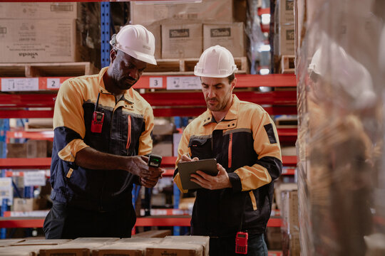 Distribution warehouse manager and client businesswoman using digital tablet checking inventory storage on shelf. Storehouse business worker and logistic engineer standing together at storage service