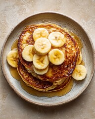a banana pancake topped with slices of banana and maple syrup or honey.