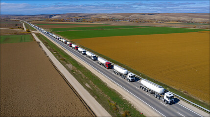 Gas Tank Trucks Travel Along Highway in Aerial View Showcasing Transportation and Logistics in Rural Landscape