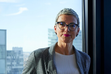Portrait of a caucasian businesswoman in a modern office with large windows and a city view,...