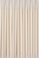 Obraz premium This close-up image shows rows of light-colored cotton swabs, arranged horizontally on a white surface
