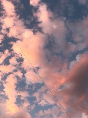 Pink sunset clouds crossed by power lines.