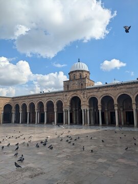 Panoramic View of the Ancient Zitouna Mosque in Tunis: White Dome and Soaring Doves Above the Sacred Terrace