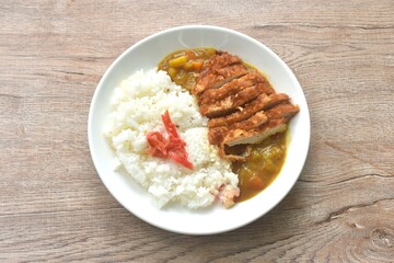 Tonkatsu crispy fried pork slice topping plain rice dressing potato and carrot in Japanese curry on plate 