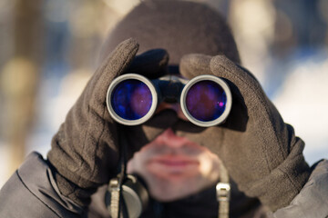 A man looks through binoculars in winter close-up.