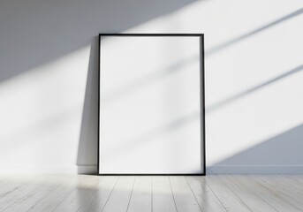 A tall black frame with a blank white space stands against a wall, illuminated by natural light creating shadows