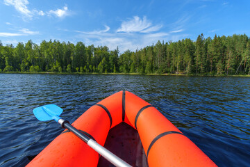 Orange packraft on a beautiful summer lake.