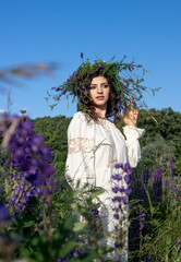 Young Woman Wearing Wildflower Crown in Blooming Countryside Landscape. Boho Girl in Traditional...