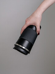 Female hand holding black thermos mug with coffee on grey background