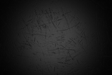 A dark, textured background featuring a dense pattern of irregular, light gray scratches and marks across a predominantly black surface, creating a distressed and aged effect with subtle vignette