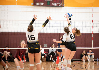 College volleyball player blocking outside hitter with one hand