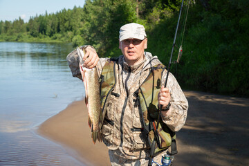 Naklejka premium Pike in the fisherman's hands. Fishing on the river.