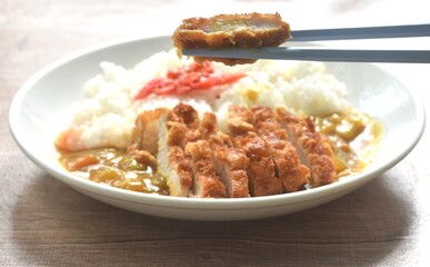 Tonkatsu crispy fried pork slice topping plain rice dressing potato and carrot in Japanese curry on plate 