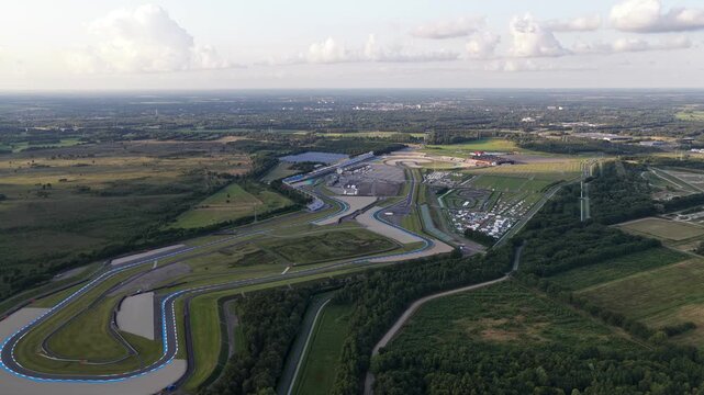 Aerial view of the entire TT Circuit Assen, nestled within a vast green landscape of forests