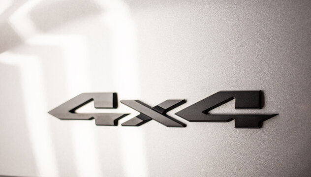 Close up of a black 4x4 emblem badge on a silver car body. Matte black 4wd four wheel drive sign on a modern vehicle tailgate automotive concept. 