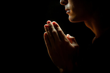 Person praying in darkness with hope.