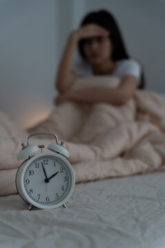 asian woman in bed late trying to sleep suffering insomnia, sleepless or scared in a nightmare, looking sad worried and stressed. Tired and headache or migraine waking up in the middle of the night.