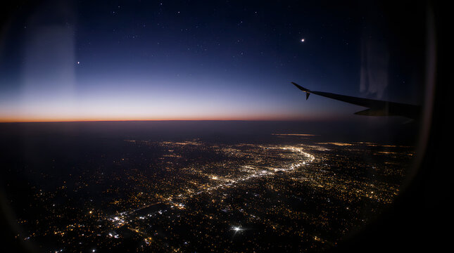 City lights at night viewed from airplane window during twilight