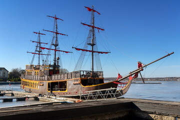 On a winter day, an ancient frigate stands at the pier, frozen in time.