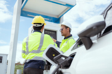 Workers operating an electric vehicle charging station in a sunny outdoor environment