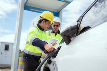 Workers operating an electric vehicle charging station in a sunny outdoor environment
