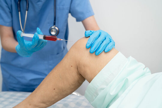 Asian doctor inject Hyaluronic acid platelet rich plasma into knee of senior woman.