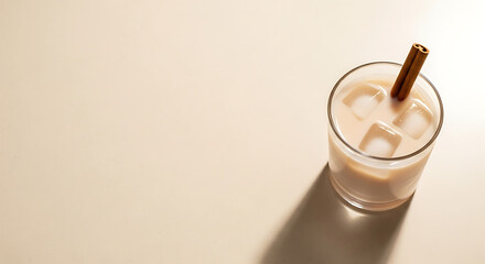 Creamy Iced Coffee with Cinnamon Stick in Glass on Beige Background