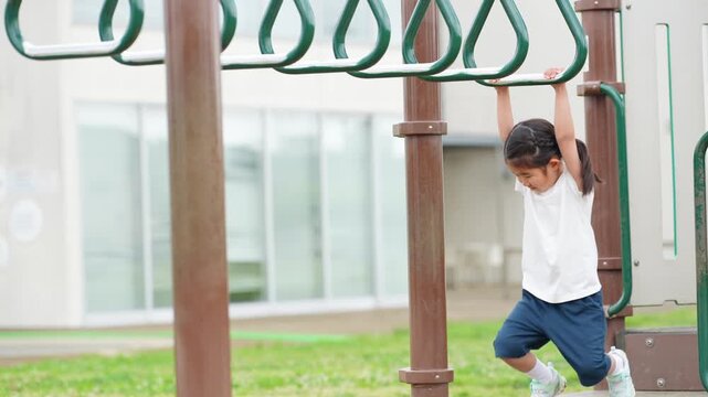 公園の雲梯で遊ぶ女の子