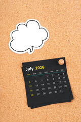 July 2026 Black calendar page and blank speech bubble with thumbtack on wooden board.
