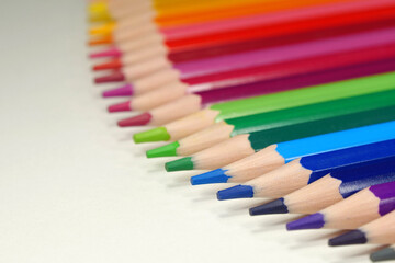 New wooden colored pencils of rainbow colors, perfectly sharpened, lie on table