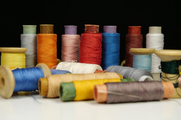 Spools with multi-colored threads on black background, close-up shot