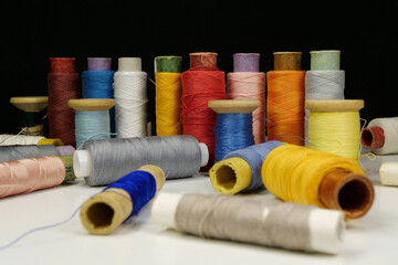 Spools with multi-colored threads on black background, close-up shot