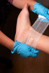 A nurse provides medical care to a man with a cut leg injury. Applying a bandage to the ankle.