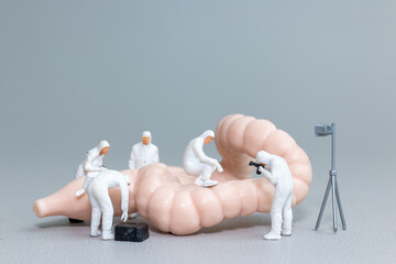 Tiny figures in hazmat suits examine a model of the human intestine