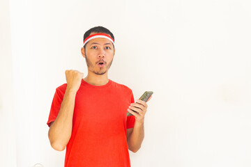 Young Indonesian man with fist clenched holding  mobile phone with headband in isolated white