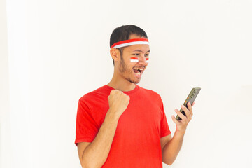 Young Indonesian man with fist clenched holding  mobile phone with headband in isolated white
