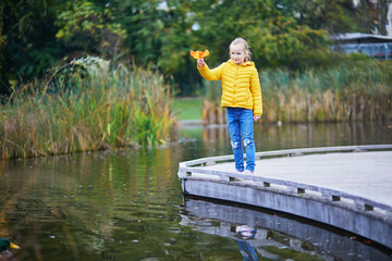Fototapeta premium Cheerful little girl enjoying her walk in autumn park in Paris, France.