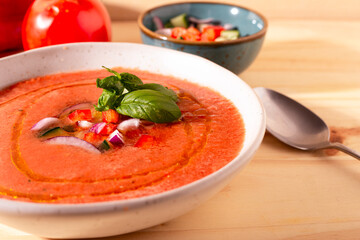 Fresh tomato and bell pepper gazpacho with basil and onion — overhead, natural light.