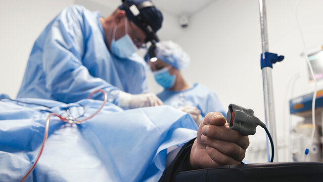 Medical professionals in surgical attire are performing a procedure in a sterile environment, focusing on patient care and advanced medical technology during a critical operation