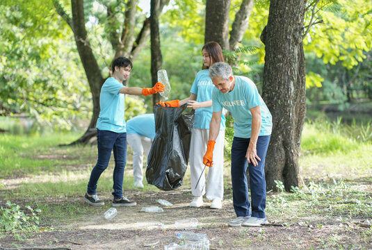 diverse group of volunteers gathering at the public park,collecting,sorting garbage and putting into trash bag,clean up environment,waste separation and recycling