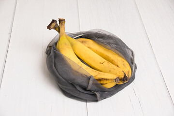 Spoiled bananas in an eco-bag on light background