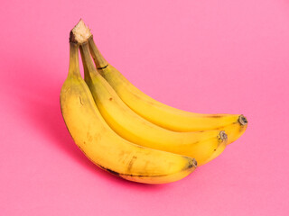 A branch of bananas with spoiled skin on a pink background