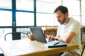 Focused freelancer working on laptop in coffee shop