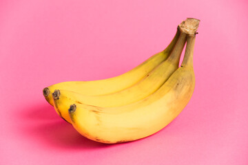 A branch of bananas with spoiled skin on a pink background