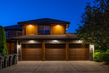 Garage door in luxury house with trees and nice landscape in Spring in Vancouver, Canada, North America. Night time on May 2025.